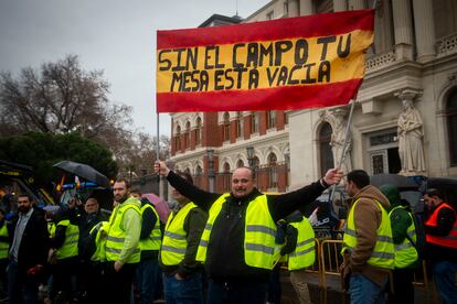 Un agricultor sujeta una pancarta con la bandera de España con el lema "Sin el campo tu mesa está vacía" frente al ministerio de Agricultura, este jueves.