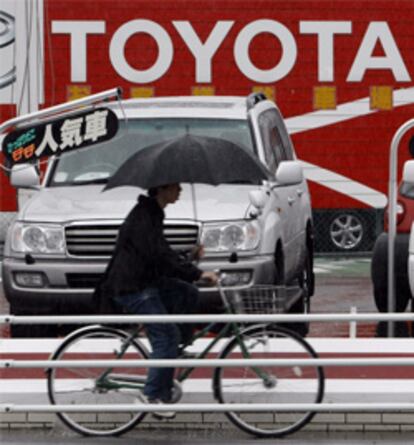 Un hombre montado en bicicleta pasa junto a un establecimiento de venta de coches de segunda mano.