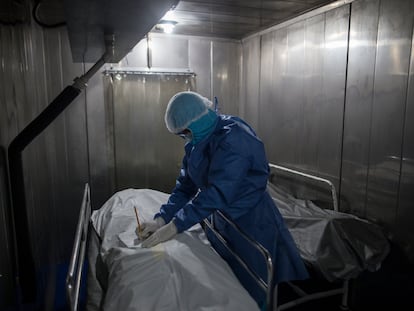 Un trabajador del hospital La Samaritana en Bogotá llena un formulario con los datos de una persona fallecida por covid-19 en la morgue de ese centro médico.