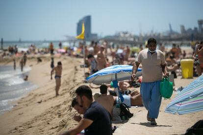 El Ayuntamiento mantiene que, para garantizar el distanciamiento social, la capacidad de las 10 playas debe ser de entre 25.000 y 38.000 personas, ya que cada usuario utiliza entre seis y nueve metros cuadrados de arena dependiendo si va solo o en grupo. En la imagen, venta ambulante en la playa de la Mar Bella de Barcelona, este sábado.