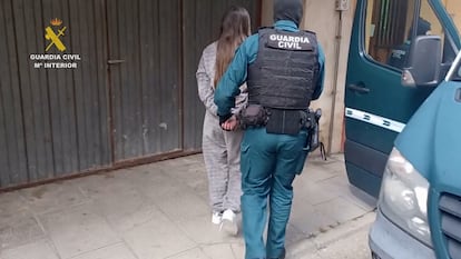 Una de las detenidas en relación con la banda a la que se le atribuyen más de 70 robos, es trasladada por un agente de la Guardia Civil.