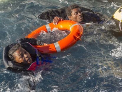 Dos inmigrantes que viajaban en las balsas hinchables son sacados del agua, a la que se lanzaron antes de ser rescatados.