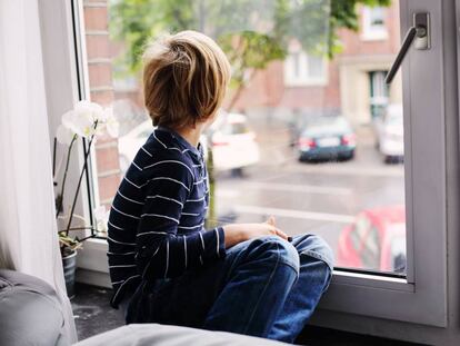 Un niño mira por la ventana de su cuarto.