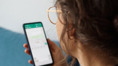 Una mujer lee un mensaje de WhatsApp en su teléfono.