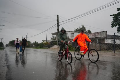 Un grupo gente caminaba bajo la lluvia antes de la llegada del huracán 'Ian' en Coloma, el lunes.