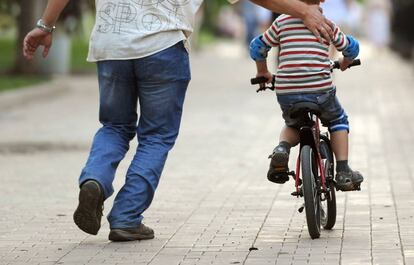 Padre ense&ntilde;a a montar en bici a su hijo. 