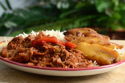 Un plato de ropa vieja, receta típica cubana a base carne mechada con arroz, frijoles y plátano frito.  