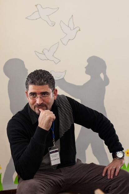 Retrato del doctor Shafik Amer, con unas palomas dibujadas en la pared, volando a su espalda. &ldquo;Vuelan los p&aacute;jaros sobre los tejados de nuestras casas, volvieron los d&iacute;as de la primavera&quot; es la frase de una canci&oacute;n que est&aacute; escrita en la pared de su centro de psicolog&iacute;a infantil.