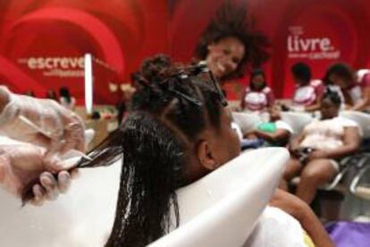 Fotografía de una mujer recibiendo un tratamiento con un producto capilar para domar el pelo ensortijado en el salón de Belleza Natural en la ciudad de Río de Janeiro (Brasil).
