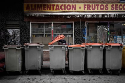 Antonio busca chatarra para vender en contenedores de basura en una calle de Madrid. Un año después de estallar la pandemia en España, la necesidad de ayuda alimentaria es omnipresente entre los sectores más castigados por la crisis económica consecuente.