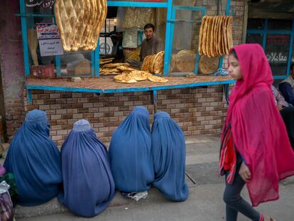 Cuatro mujeres con burka esperan pan gratis en una panadería de Kabul, el jueves.