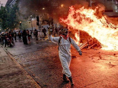 Un manifestante camina junto a un coche patrulla incendiado, durante una manifestación en Santiago (Chile), en febrero de 2021.