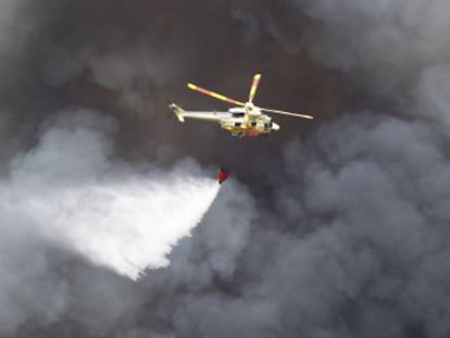 Un helic&oacute;ptero sobrevuela las &aacute;reas quemadas.