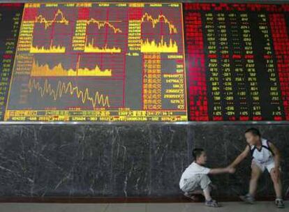 Dos niños chinos juegan junto a un panel electrónico de la Bolsa en Wuhan.