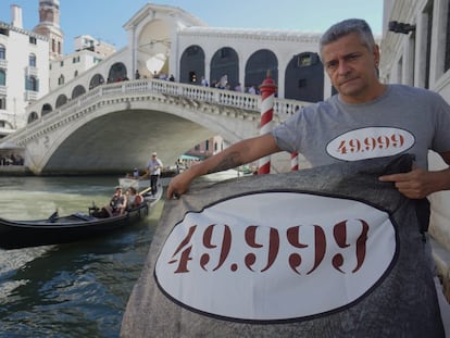 Matteo Secchi, presidente de Venessia.com, sujeta frente al puente de Rialto una pancarta que indica el número de residentes que quedan en Venecia.