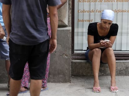 A woman uses a cellphone on a street in Havana.