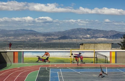 Niños de la barriada juegan en un polideportivo. Al fondo, panorama de Puerto Príncipe, la capital.