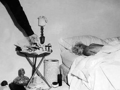 Fotografía inédita del cadáver de Marilyn Monroe en el dormitorio de su casa. Un policía, probablemente el sargento Jack Clemmons, señala las pastillas que provocaron la muerte de la actriz.