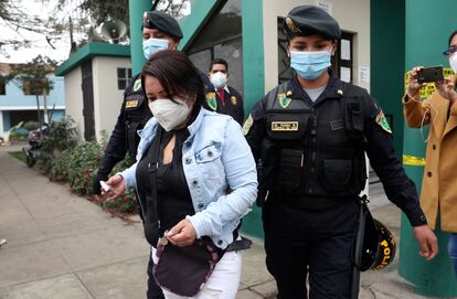 La policía escolta a una de las mujeres detenidas en la fiesta en la que 13 personas fallecieron en una estampida en Lima.