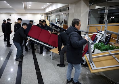 Un grupo de funcionarios retira las barricadas de muebles de las puertas del edificio de la Asamblea Nacional, después de que el presidente de Corea del Sur declarara la ley marcial, este miércoles.