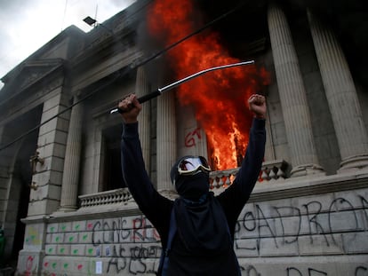 Um homem protesta em frente ao Congresso da Guatemala, que foi incendiado por alguns manifestantes.