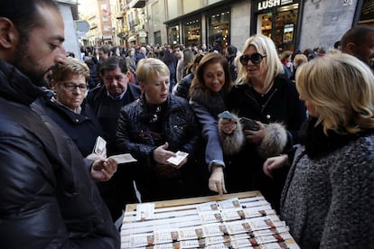 Varias personas compran lotería en un puesto callejero.