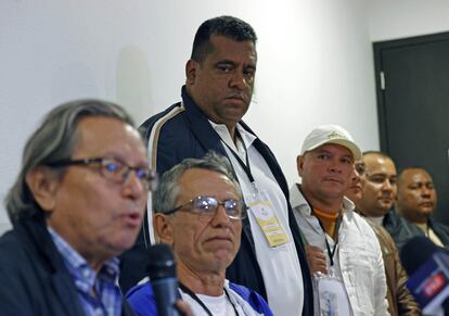 El jefe de los Comandos de Frontera, Giovanny Andrés Rojas (de pie), observa al jefe negociador del Gobierno, Armando Novoa (a la izquierda), y al de la Coordinadora Nacional Ejército Bolivariano, 'Walter Mendoza', durante una rueda de prensa en Bogotá, el martes 26 de noviembre de 2024.