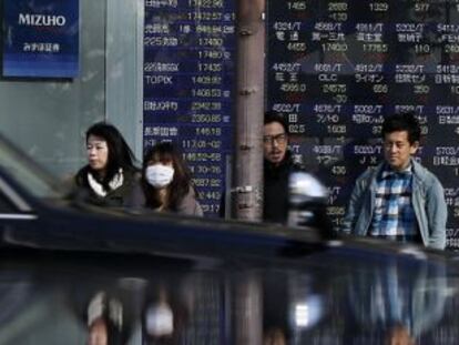 Peatones frente a un panel de cotizaci&oacute;n en Tokio