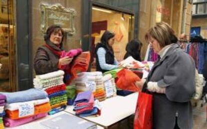 Una mujer observa las ofertas de uno de los puestos de un mercado de gangas. EFE/Archivo