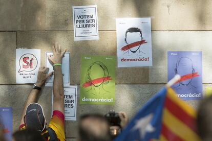 Un joven pega carteles a favor de la celebración del referéndum independentista en Barcelona.