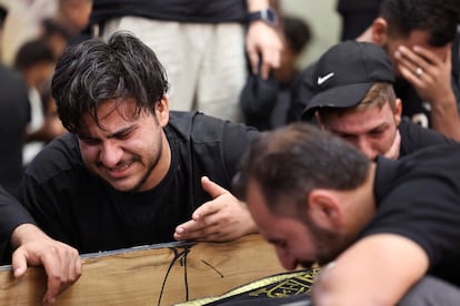 Varios hombre lloran durante el funeral de algunas de las víctimas que murieron en el incendio comercial en Kut, este jueves.