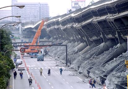 Una enorme grúa levanta los coches destruidos por un terremoto, cuya intensidad fue de 7,2 en la escala de Ritcher, en una carretera de Kobe (Japón).