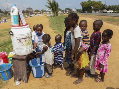 Una voluntaria del programa Mujeres en Paz lava las manos a unos niños liberianos. / EFE