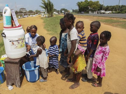 Una voluntaria del programa Mujeres en Paz lava las manos a unos niños liberianos. / EFE