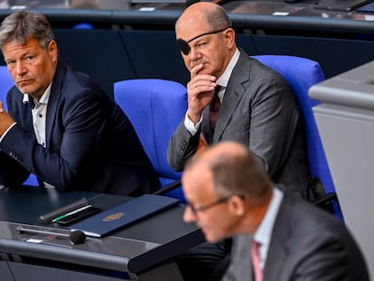 El canciller alemán, Olaf Scholz, con un parche en el ojo tras un accidente leve haciendo deporte, y el ministro de Economía y Clima, Robert Habeck, escuchan al líder de los democristianos, Friedrich Merz, este viernes en el Bundestag.