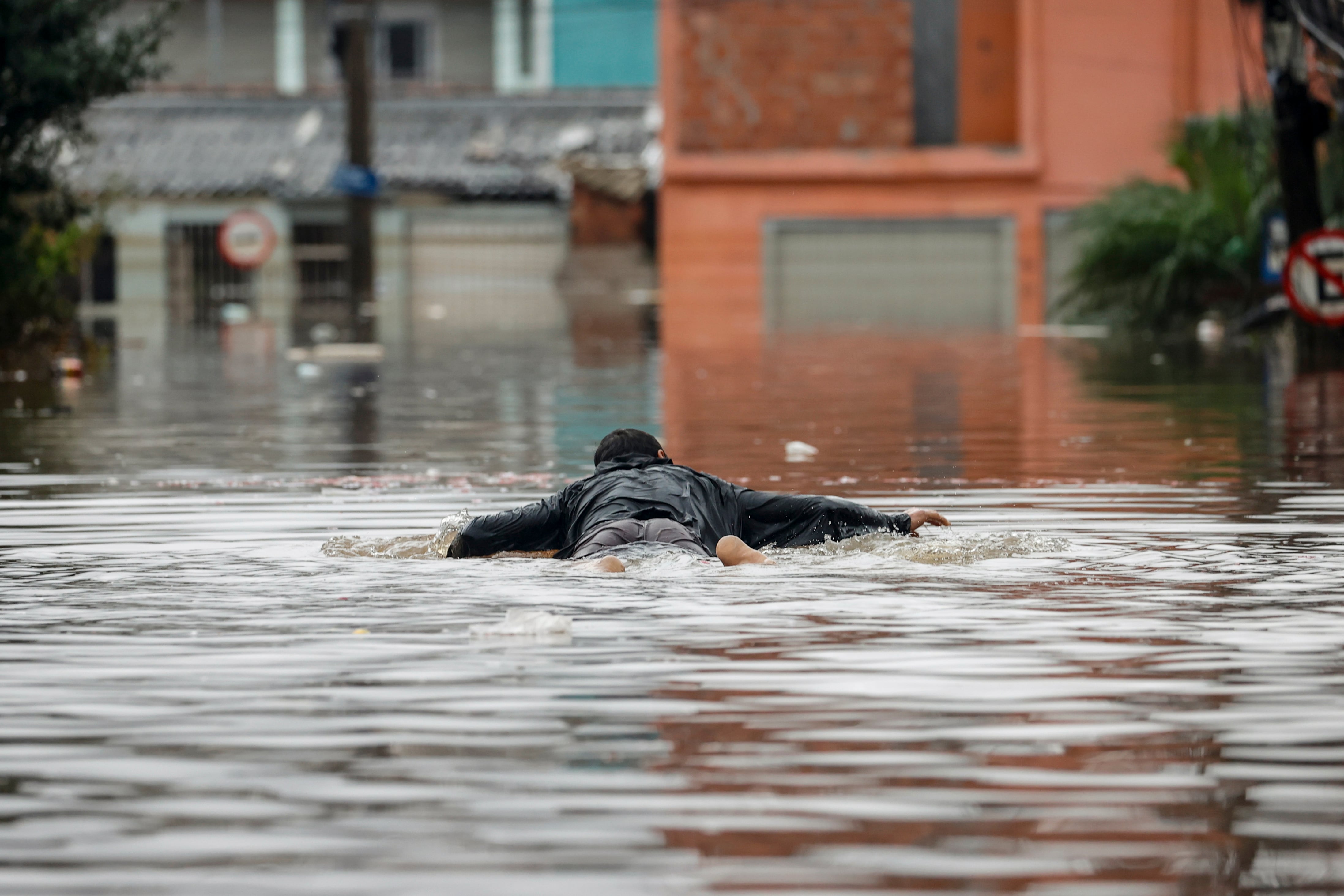 Un hombre se transporta sobre una tabla en las calles inundadas del barrio Humaita, en Porto Alegre (Brasil). 