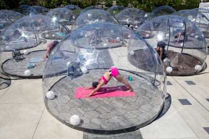 Participantes de una clase de yoga al aire libre, lo practican dentro de una cúpula para facilitar el distanciamiento y los protocolos adecuados para prevenir la propagación del coronavirus, en Toronto (Canadá).