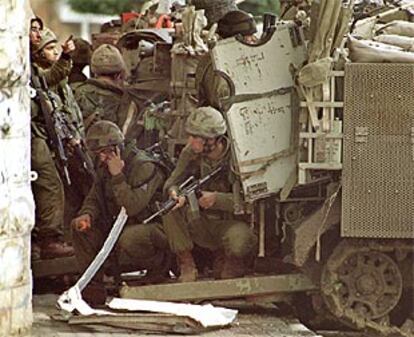 Un grupo de soldados israelíes, agazapados tras un tanque en Tulkarem.