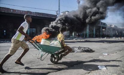 Un hombre carga a un menor en una carretilla cerca a una barricada en Puerto Príncipe (Haití) el lunes 9 de julio.