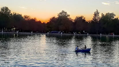 Varias personas pasean en una barca por El Retiro.