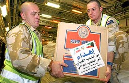 Dos <i>marines</i> transportan una caja con ayuda humanitaria para Irak ayer en la base británica de Sir Galahad.