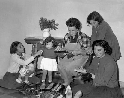 Una madre junto a sus hijas limpiando los zapatos de la familia, en una imagen de archivo de los años 60.