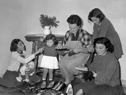 Una madre junto a sus hijas limpiando los zapatos de la familia, en una imagen de archivo de los años 60.