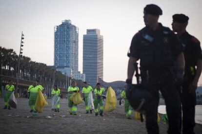 Operarios limpian la playa de la Barceloneta tras la celebración de la verbena de San Juan.