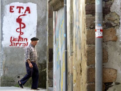 Un hombre pasa al lado de un grafiti con el logo de ETA.