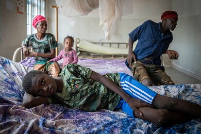 Mohamed Camara, de 10 años, descansa en una cama del Centro de Salud de Tamita en junio de 2025. Lo acompañan sus padres y su hermana pequeña. A Mohamed le han diagnosticado malaria en medio de una crisis de salud global por los recortes de EE UU a la ayuda exterior. 