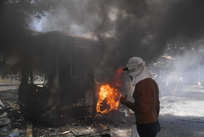 Un manifestante de la oposición junto a un autobús del gobierno incendiado durante los enfrentamientos con soldados.
