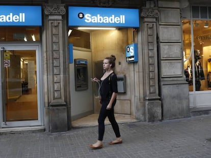 Una dona passa per una oficina de Banc Sabadell, a Barcelona.