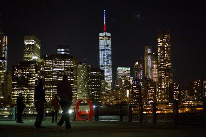 Unos viandantes observan desde la distancia The One World Trade Center, el edificio más alto de la zona este de Nueva York (EE UU), iluminado con los colores de Francia en solidaridad con las víctimas de los atentados perpetrados.