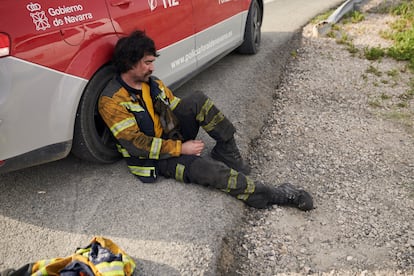 Un bombero forestal descansa a la sombra de un coche de Policía Foral durante el incendio forestal en la Sierra de Leyre.